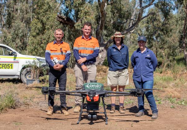 Four people in front of Dendra Systems drone
