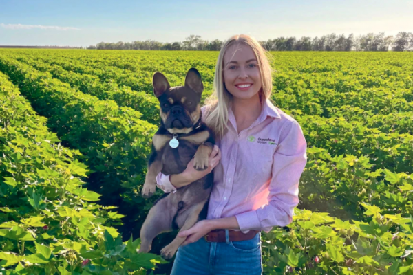 Cotton marketer Jess Strauch pictured holding her dog standing in a cotton paddock.